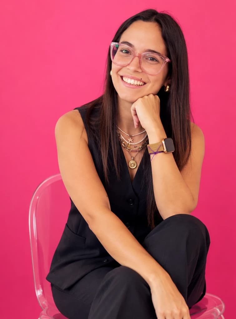 Julieta, la persona detrás de Redes con Juli, sonriendo sobre un fondo fucsia